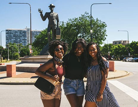 Friends in front of the Monument to the Great Northern Migration statue in Chicago’s Bronzeville.